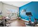 Inviting home office with a bright blue accent wall, hardwood floors, large windows, and an exercise bike at 3929 Glenlake Garden Dr, Raleigh, NC 27612