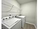 Bright laundry room featuring white washer and dryer units, plus a shelf for storage and gray wood-look tile floors at 5014 Kota St, Raleigh, NC 27610