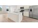 Bright kitchen with stainless steel appliances, island, white cabinetry and wood flooring at 609 Silverado Sunset Loop, Wendell, NC 27591