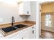 Close-up of a kitchen sink with white cabinets, wood counters, and modern fixtures at 610 Peele St, Burlington, NC 27215