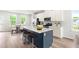 Open kitchen features island with seating, stainless appliances, white cabinets and spacious design for entertaining at 611 Silverado Sunset Loop, Wendell, NC 27591