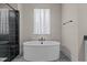 Soaking tub and a sleek glass shower with black tiling and fixtures at 7100 Hasentree Club Dr, Wake Forest, NC 27587