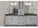 Modern bathroom with dual vanities featuring black countertops, decorative mirrors and cabinet storage space at 7100 Hasentree Club Dr, Wake Forest, NC 27587