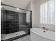 Contemporary bathroom boasts a glass enclosed shower with black tiling and fixtures and a soaking tub at 7100 Hasentree Club Dr, Wake Forest, NC 27587
