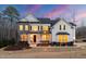 Stunning two-story home with stone accents, landscaped yard, and professional lighting at twilight at 7100 Hasentree Club Dr, Wake Forest, NC 27587