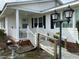Inviting front porch with ramp, classic columns, decorative lighting, and black shutters on windows at 736 Core Rd Rd, Dunn, NC 28334