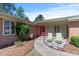 Inviting home featuring a coral front door, lush landscaping, brick accents, and cozy chairs near the entrance at 7516 Mourning Dove Dr, Sanford, NC 27332