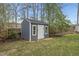 Backyard shed with gray siding, white trim and door, and gable roof design at 8304 Circlewood Ct, Raleigh, NC 27615