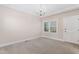 Bright, carpeted bedroom with a large window, chandelier lighting, and a white door at 100 Dunedin Ct, Cary, NC 27511