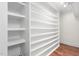 Spacious walk-in closet with custom built-in shelving and hardwood floor at 100 Dunedin Ct, Cary, NC 27511