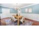 Light and airy dining room featuring hardwood floors, blue walls, and a modern chandelier above the dining table at 100 Dunedin Ct, Cary, NC 27511