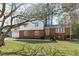 Brick home with a manicured lawn and mature trees providing shade at 1004 Plateau Ln, Raleigh, NC 27615