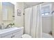 Bathroom featuring a shower/tub combo with patterned shower curtain, white tile, toilet, and sink with vanity at 101 Newell St, Durham, NC 27705