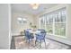 Light-filled dining room with blue chairs, white table, large windows, and neutral colored walls and floors at 101 Newell St, Durham, NC 27705