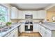 Well-lit kitchen featuring stainless steel appliances, granite countertops, and white cabinetry at 101 Newell St, Durham, NC 27705
