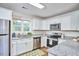 Well-lit kitchen with stainless appliances, granite countertops, and white cabinets with a view of the outdoors at 101 Newell St, Durham, NC 27705