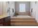 Bright bathroom showcasing a large soaking tub with tile surround and natural light from the window at 113 Kings Castle Dr, Apex, NC 27502
