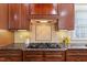 Close up of a cooktop and backsplash in a kitchen with granite countertops and wooden cabinets at 113 Kings Castle Dr, Apex, NC 27502