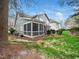 Backyard view featuring a screened porch, red umbrella, mature trees, and lush green lawn at 1428 Heritage Links Dr, Wake Forest, NC 27587