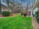 Spacious backyard features a well-maintained lawn, mature trees, and a cozy patio seating area with a red umbrella at 1428 Heritage Links Dr, Wake Forest, NC 27587