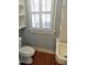 Small bathroom with window with blinds, toilet, and small sink with built in storage at 1703 St. Mary'S St, Raleigh, NC 27608