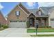 Charming brick home featuring a well-manicured lawn, covered porch with decorative columns, and an attached two-car garage at 1914 Tweed Ln, Burlington, NC 27215