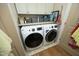 Convenient laundry area with modern washer and dryer units and overhead storage cabinets at 1914 Tweed Ln, Burlington, NC 27215