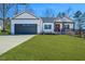 Charming home showcasing a manicured lawn, a gray garage door, and a welcoming red front door at 271 Sacred Fire Rd, Louisburg, NC 27549