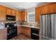 Kitchen area features stainless steel refrigerator, black appliances, and wood cabinets at 3007 Cardinal Lake Dr, Durham, NC 27704