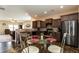 Open kitchen area with dark cabinets, a glass-top table and chairs, stainless-steel appliances, and hardwood floors at 303 Fortress Dr, Morrisville, NC 27560