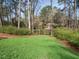 Backyard showcasing a lush green lawn, landscaping, and glimpses of neighboring homes in a wooded setting at 3321 Marblehead Ln, Raleigh, NC 27612