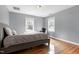 Serene bedroom features hardwood floors, two windows, and a cozy gray upholstered bed at 3424 Forest Oaks Dr, Chapel Hill, NC 27514