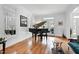 Bright living room featuring hardwood floors, a grand piano, large windows, and French doors to the backyard at 3424 Forest Oaks Dr, Chapel Hill, NC 27514