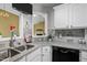 Close-up of a kitchen featuring grey tile backsplash, black appliances, gray countertops and white cabinetry at 4 Applewood Sq, Durham, NC 27713