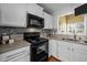 Kitchen showcasing black appliances, grey countertops, white cabinets, and grey tiled backsplash at 4 Applewood Sq, Durham, NC 27713
