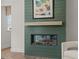 Modern fireplace with green shiplap and a light-colored wooden mantle at 4706 Cypress Tree Ln, Raleigh, NC 27612