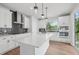 Modern kitchen featuring white cabinets, gray backsplash, kitchen island and stainless steel appliances at 4706 Cypress Tree Ln, Raleigh, NC 27612
