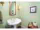 Powder room featuring a white pedestal sink, gold-toned fixtures, and sage green walls at 4808 Clubview Ct, Fuquay Varina, NC 27526