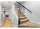 Staircase featuring tan carpeted steps, white spindles, and a dark wood handrail, leading to the upper level at 514 Peele St # A, Burlington, NC 27215