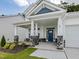 Inviting front porch featuring stone pillars, a blue door, and a covered entryway, creating a welcoming first impression at 789 Old Station Pointe, Angier, NC 27501