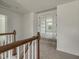Upstairs hallway featuring carpet, white walls, wood railing and staircase that lead to the rooms of the home at 789 Old Station Pointe, Angier, NC 27501