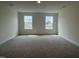 Spacious carpeted living room with two windows and neutral walls, offering a bright and airy feel at 789 Old Station Pointe, Angier, NC 27501