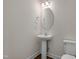 Powder room featuring a pedestal sink, round mirror, a light fixture, toilet and dark wood flooring at 789 Old Station Pointe, Angier, NC 27501