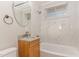 Updated bathroom featuring modern fixtures, stylish vanity, tub with marble-like tile surround and a round mirror at 820 Newcombe Rd, Raleigh, NC 27610