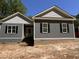 New construction home featuring gray siding, brick foundation, black shutters, and a covered front entryway at 977 Lewis Rd, Zebulon, NC 27597