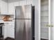 Stainless steel refrigerator and nearby pantry in a kitchen with white cabinetry at 1051 Wirewood Dr # 202, Raleigh, NC 27605