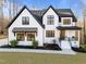 Charming two-story farmhouse-style home with black framed windows, a covered porch, and beautifully landscaped front yard at 110 Black Swan Dr, Youngsville, NC 27596