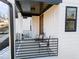 A view of the home's front porch with modern patio furniture, a black railing and white columns at 110 Black Swan Dr, Youngsville, NC 27596