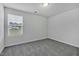 Empty bedroom with neutral gray walls, plush carpeting, and a window overlooking the backyard at 1131 Pate Farm Ln, Durham, NC 27703