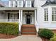 Inviting front porch with brick steps, white columns, and a decorative wreath on the black front door at 1188 The Preserve Trl, Chapel Hill, NC 27517